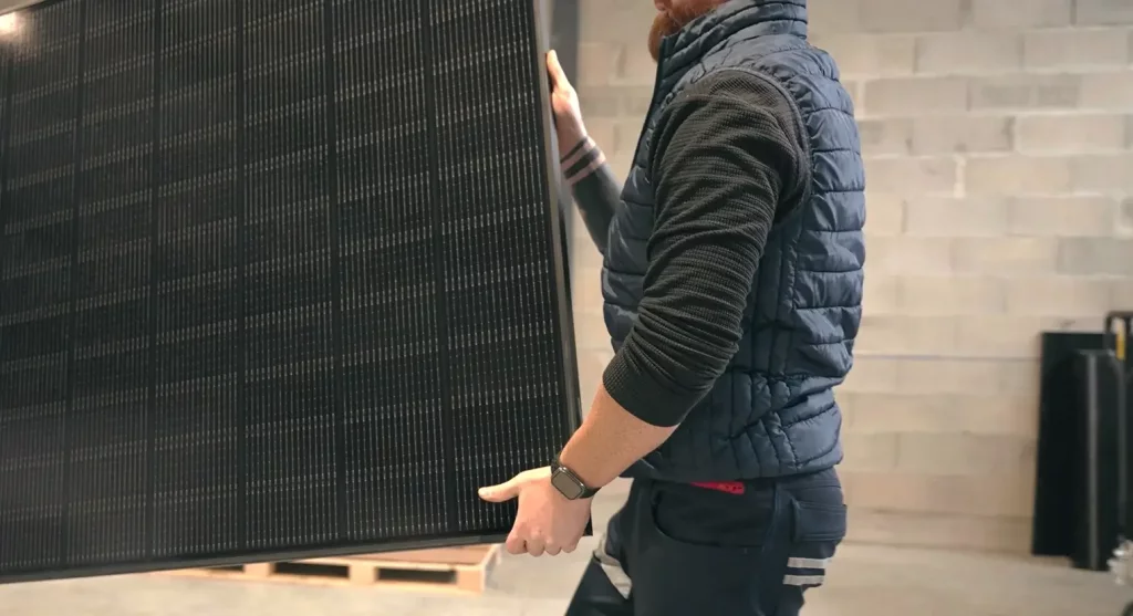 Technicien qui porte un panneau photovoltaïque
