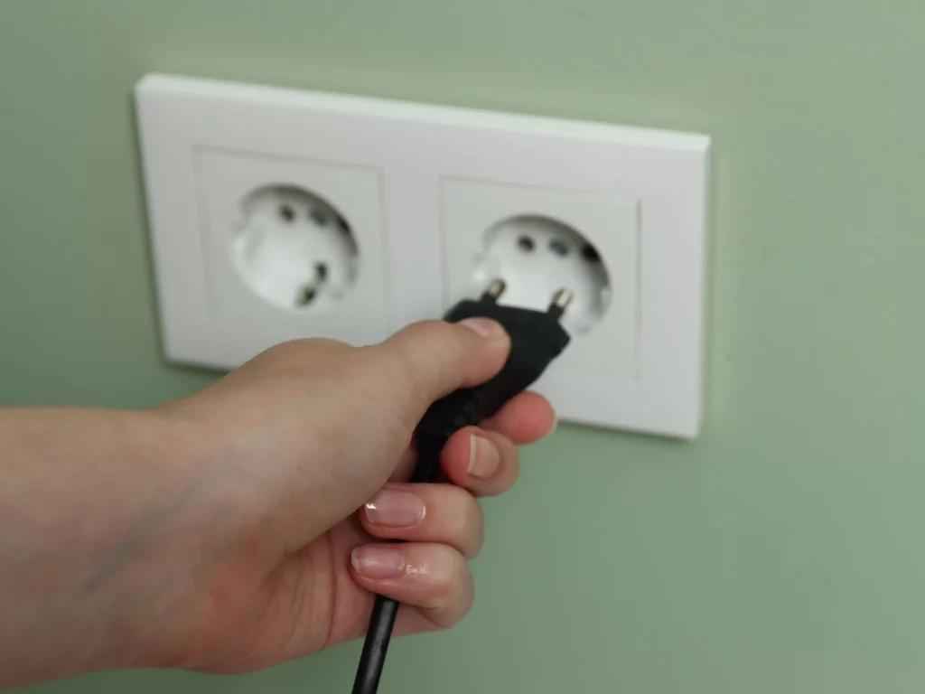 Main qui branche un câble d'alimentation sur une prise électrique