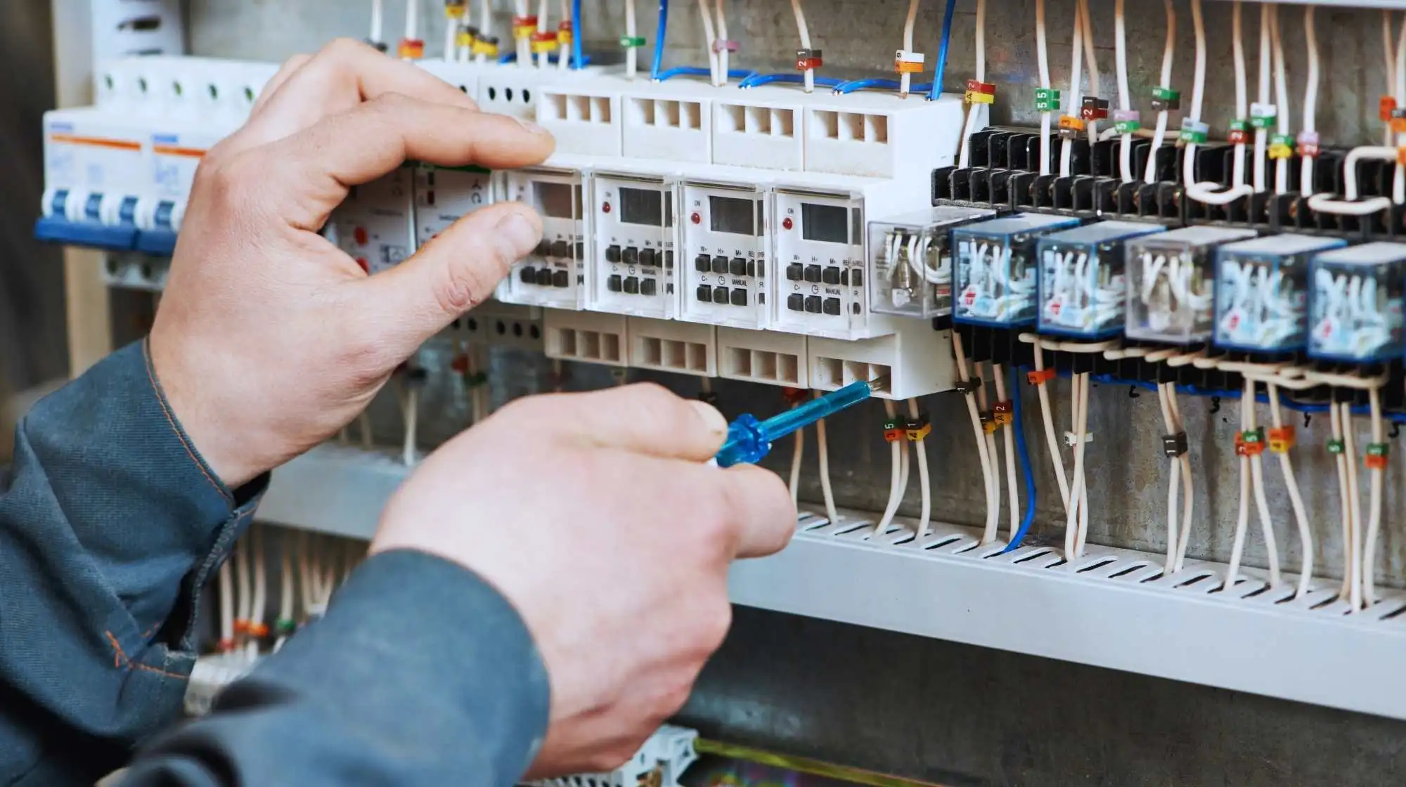 Les mains d'un technicien doté d'un outil travaillent sur un tableau électrique