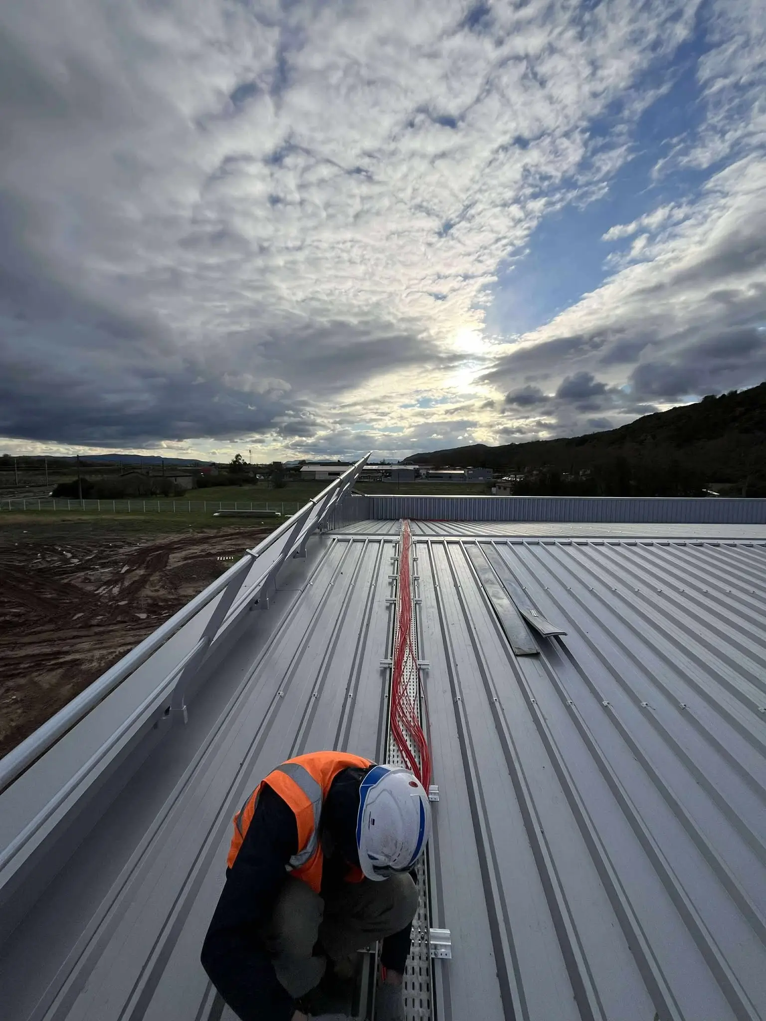 Technicien photovoltaique sur le toit d'une entreprise qui réalise le passage de cable d'une installation