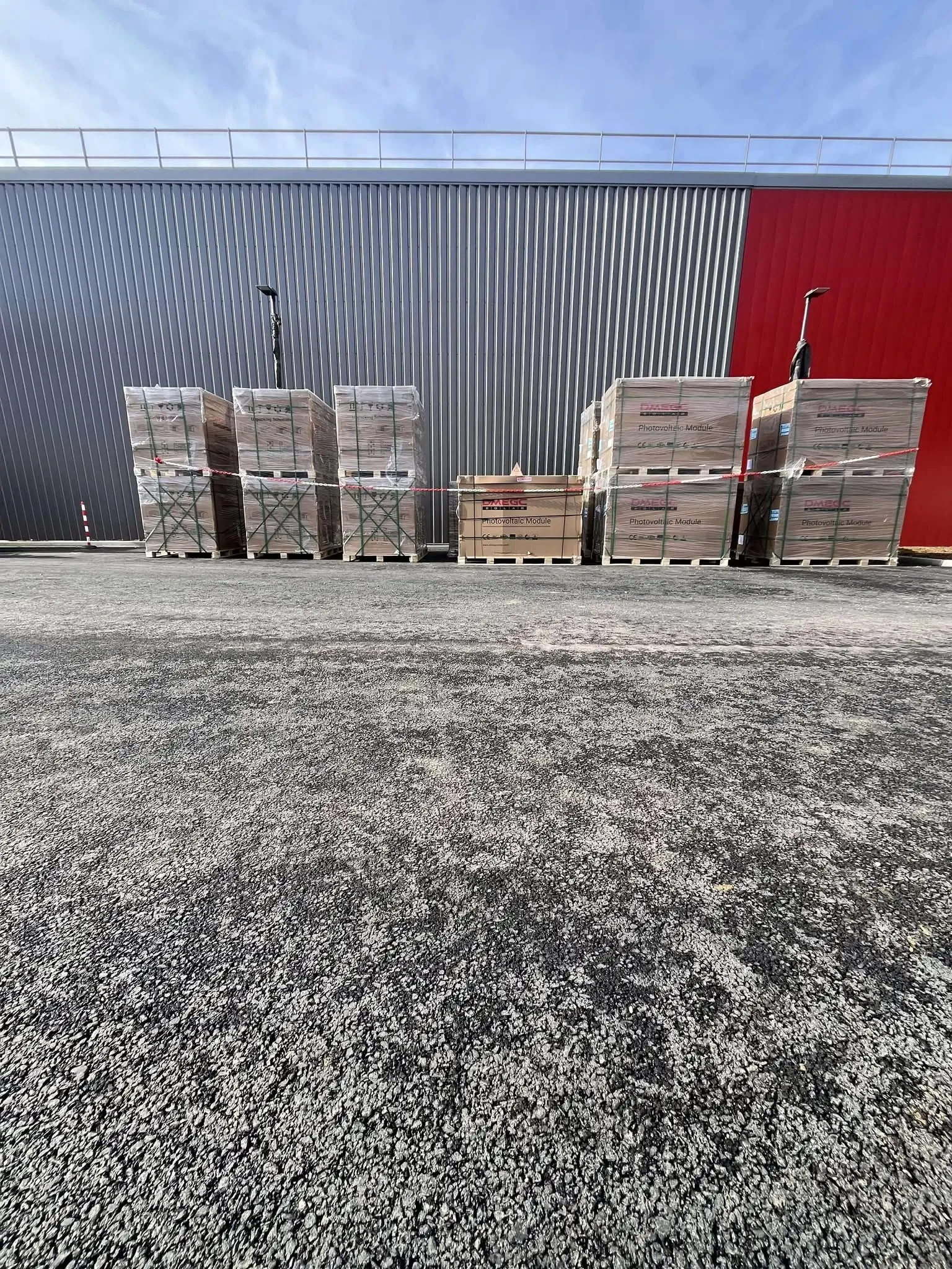 Palettes de modules photovoltaïques de la marque DEMGC posées devant l'entreprise à équiper.