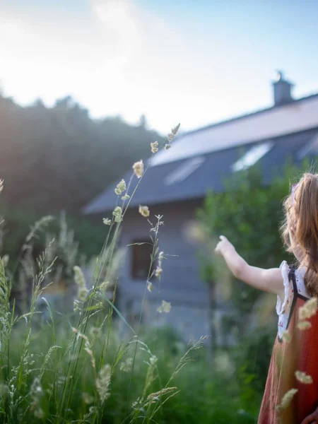 Petite fille devant la maison familiale â côté des panneaux photovoltaïques sous les rayons du soleil