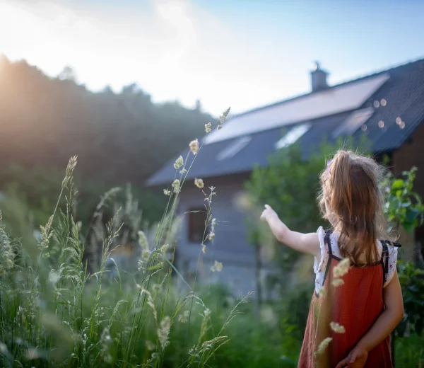 Petite fille devant la maison familiale â côté des panneaux photovoltaïques sous les rayons du soleil