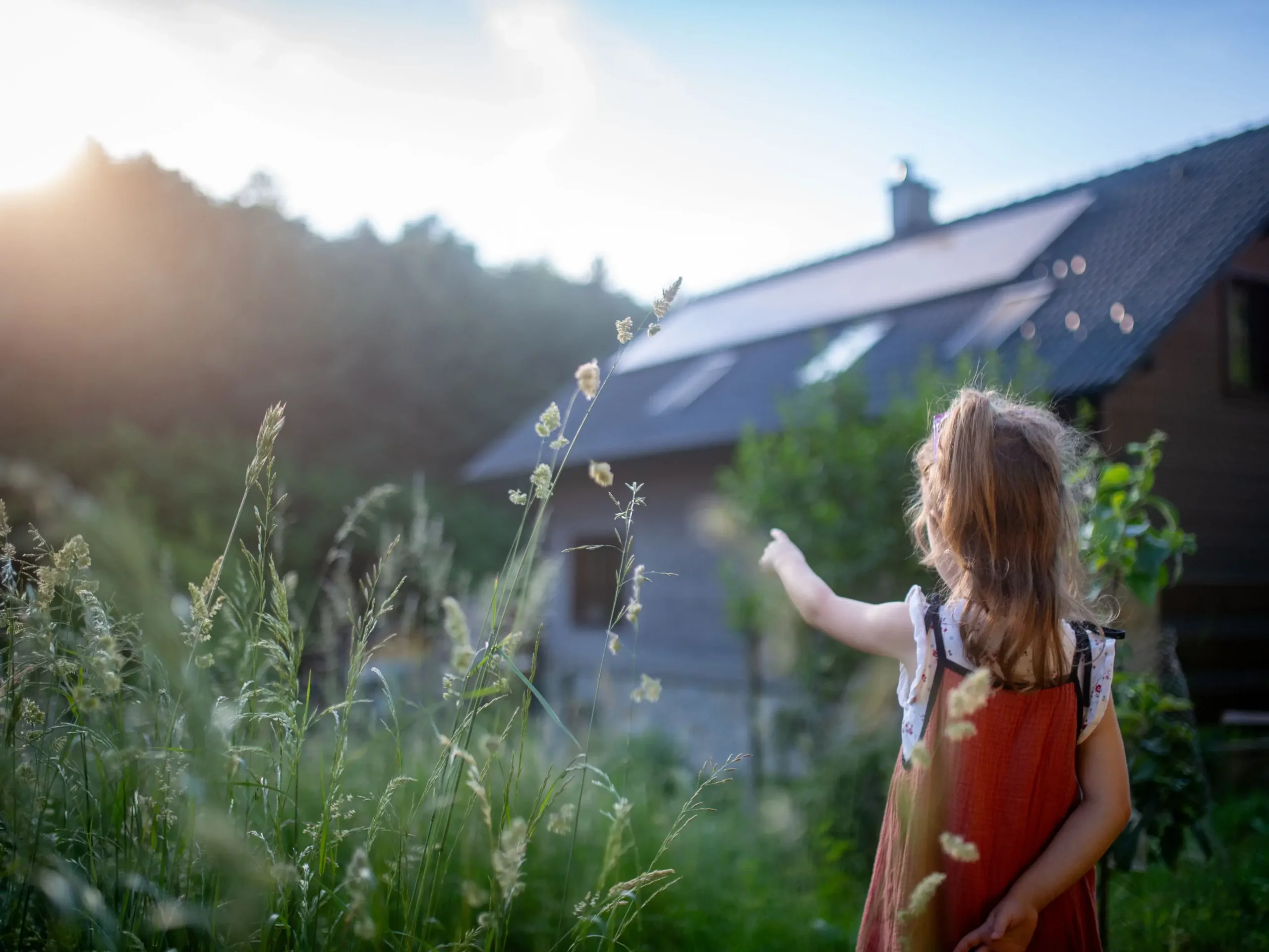 Petite fille devant la maison familiale â côté des panneaux photovoltaïques sous les rayons du soleil