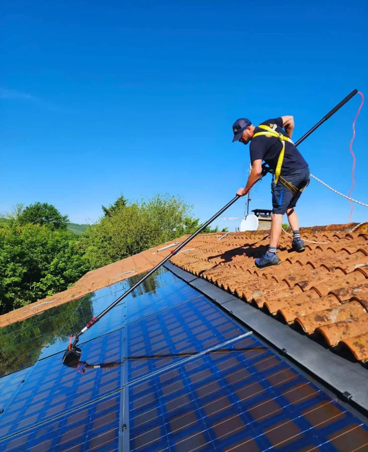 Technicien, qui nettoie des panneaux photovoltaïques à la brosse souple