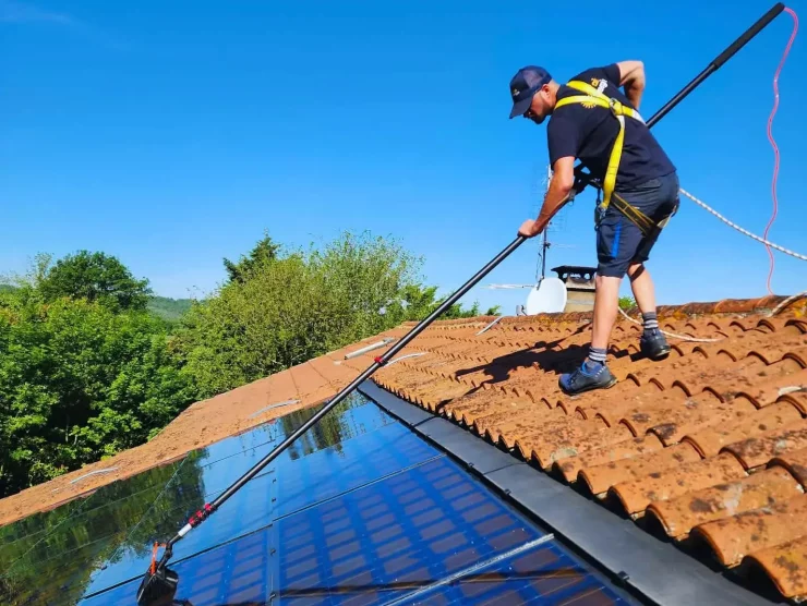 Technicien, qui nettoie des panneaux photovoltaïques à la brosse souple
