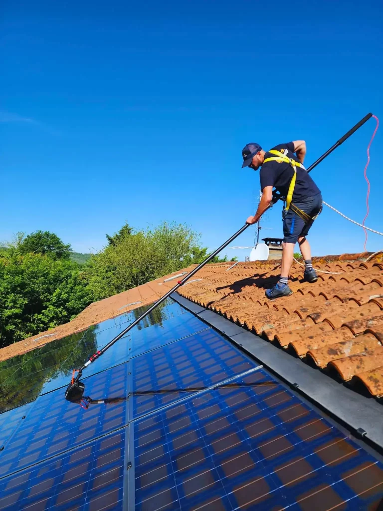 Technicien, qui nettoie des panneaux photovoltaïques à la brosse souple