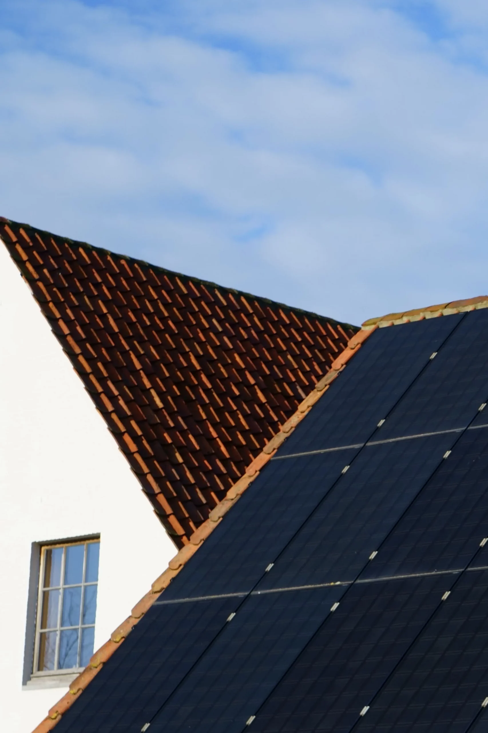 Panneaux photovoltaïques posés sur un toit en pente avec des tuiles.