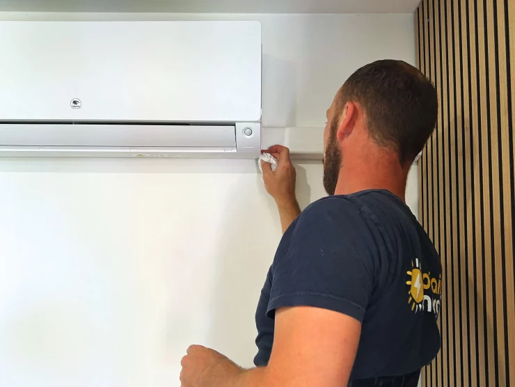 Michel, technicien électricien chez sol'air energie nettoie la climatisation intérieure qui vient d'être posée