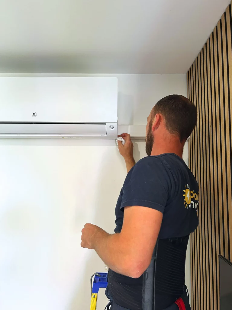 Michel, technicien électricien chez sol'air energie nettoie la climatisation intérieure qui vient d'être posée